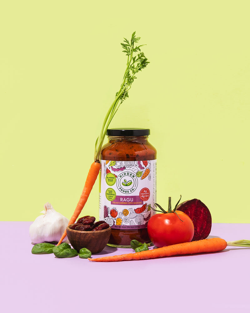 Jar of Ragú pasta sauce with fresh vegetables on a light green and purple background